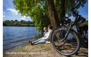 Zwei Frauen mit ihren Rädern machen eine Pause am Seeufer
