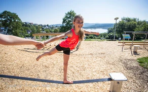 Kleines Mädchen balanciert über Slack-Line im Bewegungspark