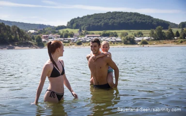 Eine junge Familie planscht im See und genießt das kühle Nass.