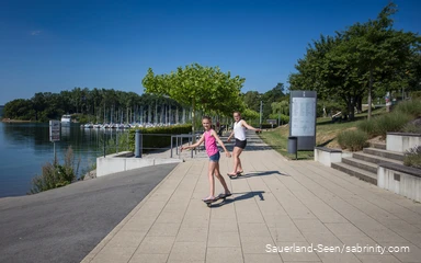 Zwei junge Mädchen auf dem Skateboard auf der Seepromenade